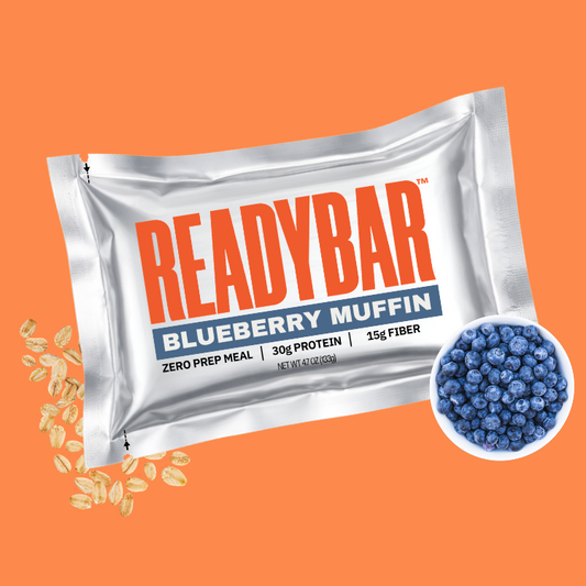 READYBAR Blueberry Muffin meal replacement bar packaging on an orange background with fresh blueberries and oats.